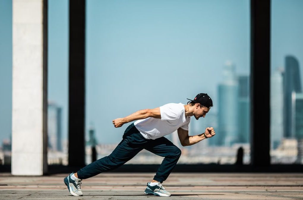 Dynamic shot of a young man sprinting outdoors in an urban setting with skyscrapers in the background.